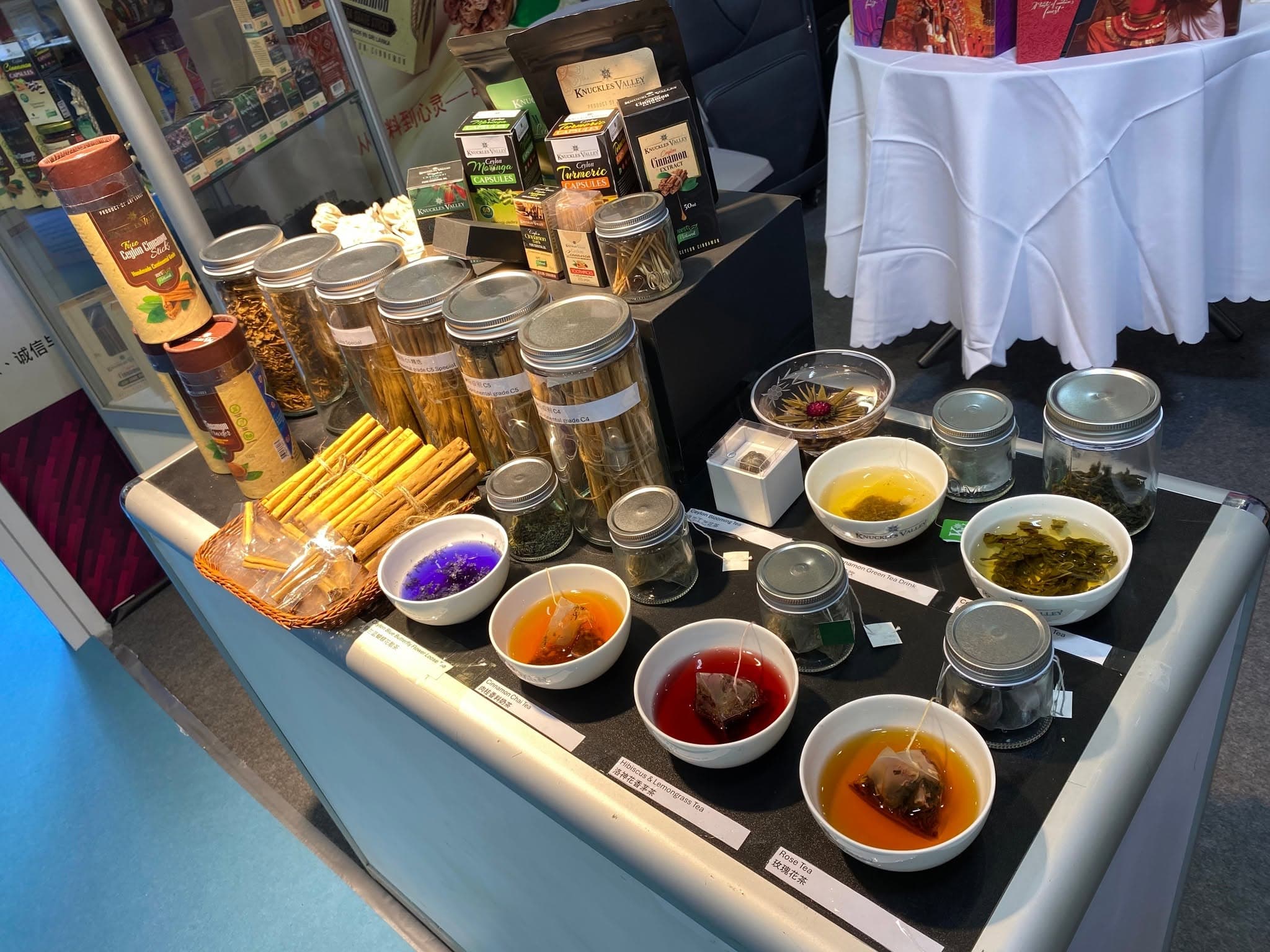 An exhibition counter holds cinnamon jars, packaged products and colourful tasting bowls.