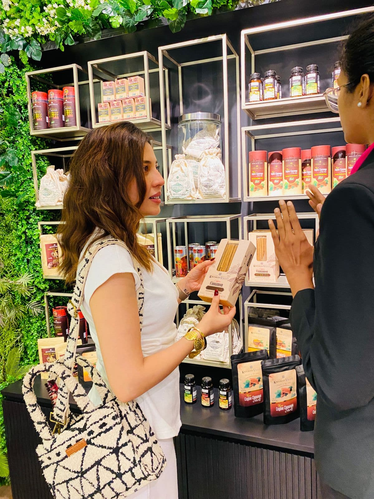 A visitor holds a cinnamon package while speaking with a team member.