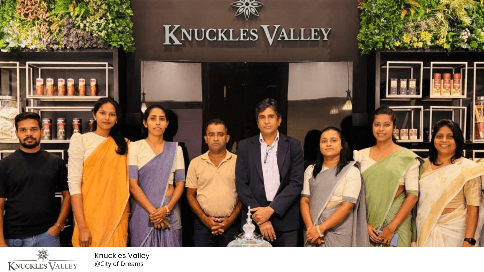 A group stands together in front of the Knuckles Valley sign and display shelves at City of Dreams.
