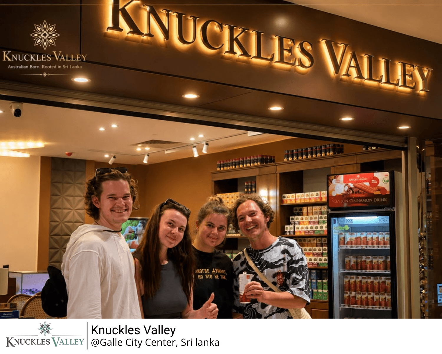 Four visitors stand beneath the illuminated Knuckles Valley storefront sign.