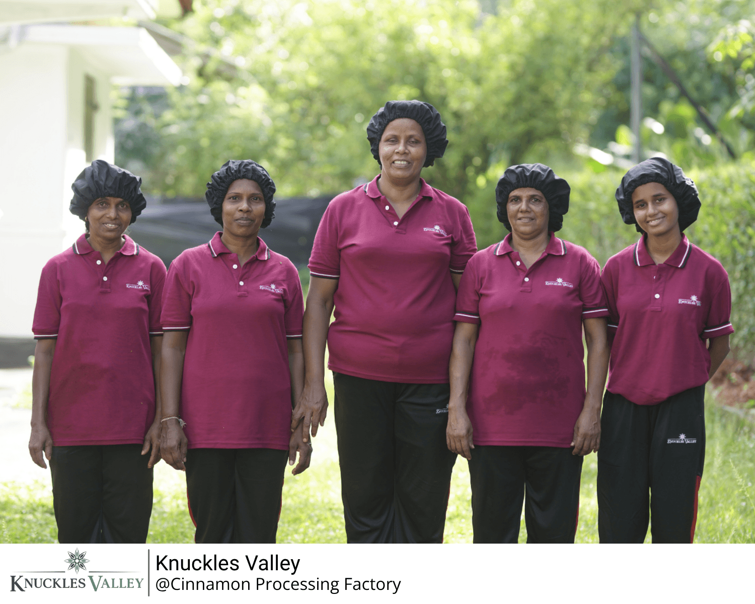 Five team members in matching maroon polo shirts stand together outdoors.
